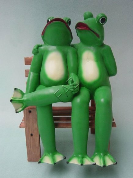 Two green colored bright frogs resting on a bench sculpture 47cm height c491